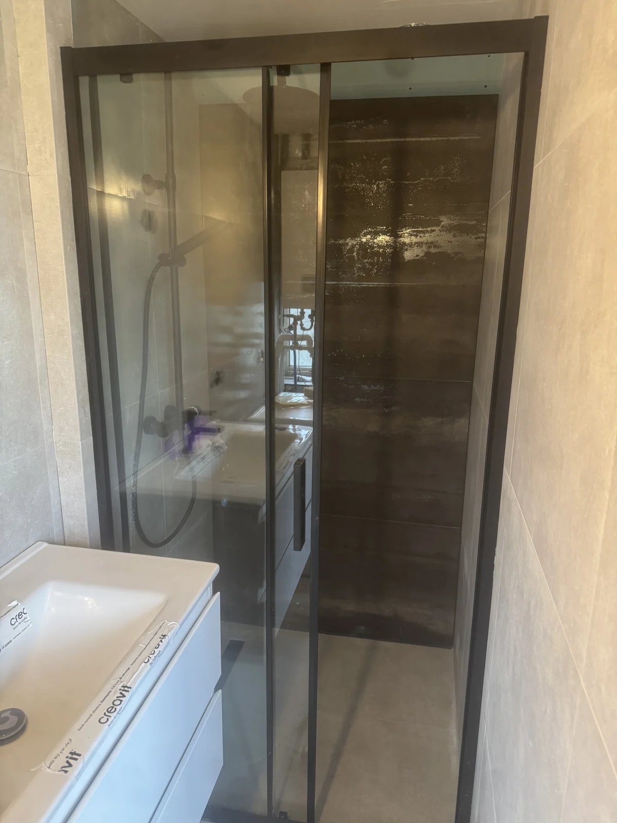 Afgeronde badkamer met glazen douchewand en grootformaat tegels — Batur Bouw