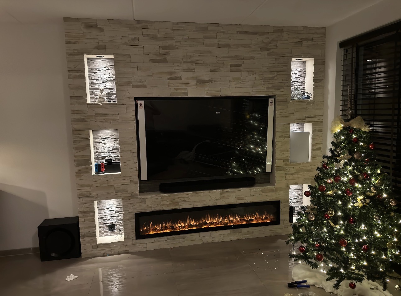 Cinewall met steenlook bekleding, verlichte nissen en haard — eigen project Batur Bouw